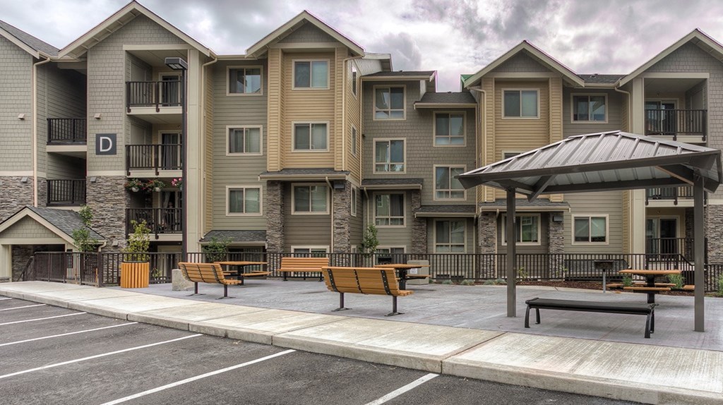 an empty parking lot with benches in front of an apartment building