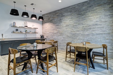 a dining room with round tables and chairs and a kitchen