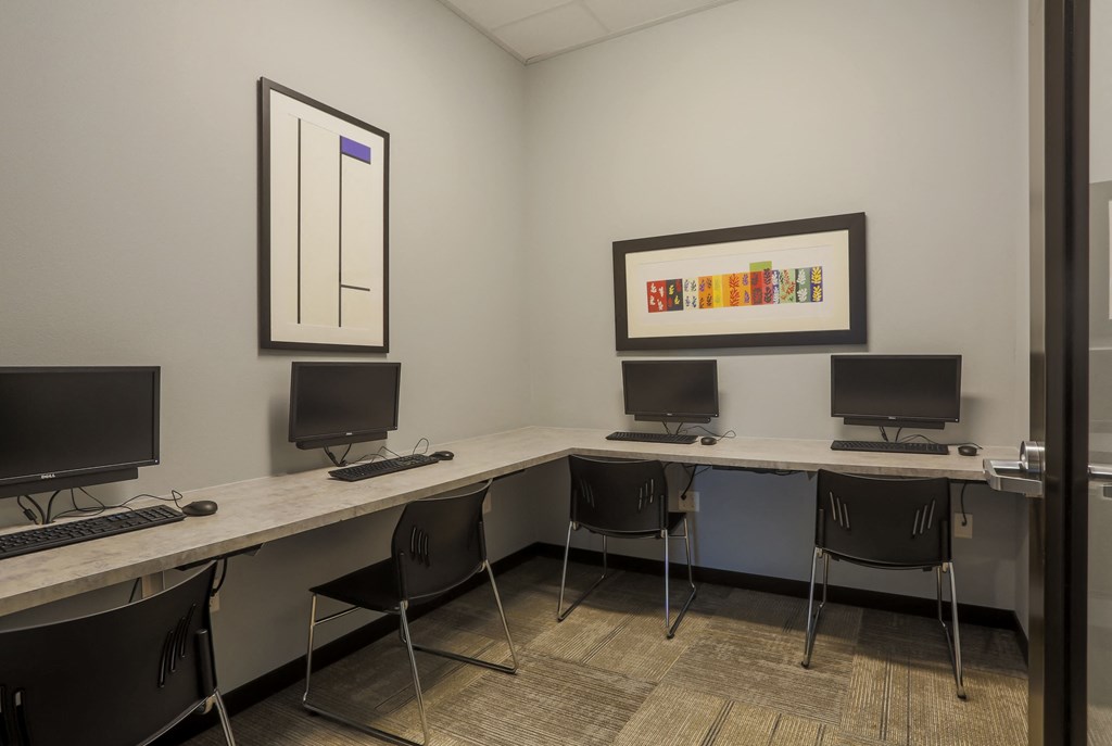 a computer room with three computers on desks and chairs