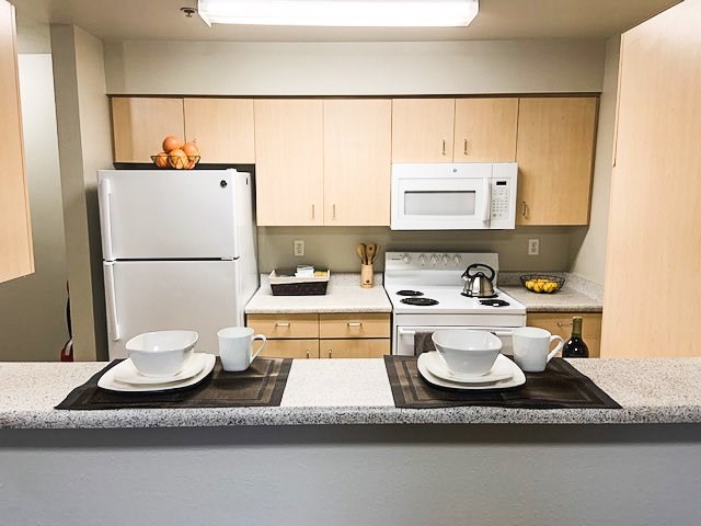 A kitchen with a white refrigerator and a white microwave above a stove.