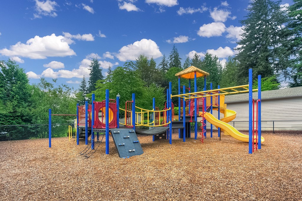 A playground with a yellow slide and a red and blue structure.
