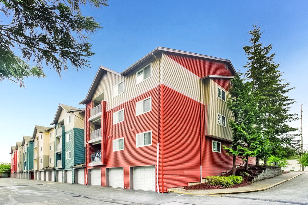 A red and beige apartment building with a parking lot in front.
