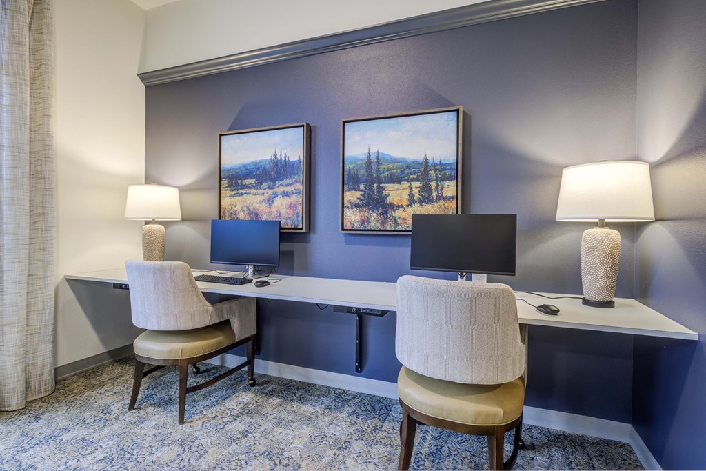 two desks with two chairs and two computer monitors in a room with a blue wall at Ovation at Meeker, Kent Washington