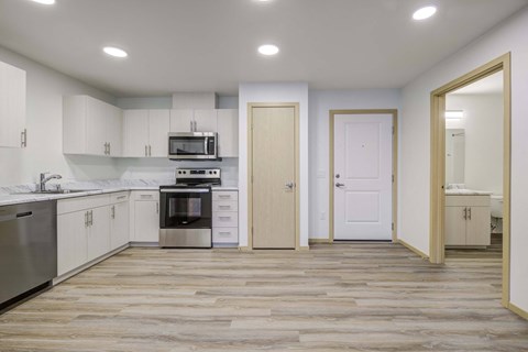 an empty kitchen with white cabinets and stainless steel appliances