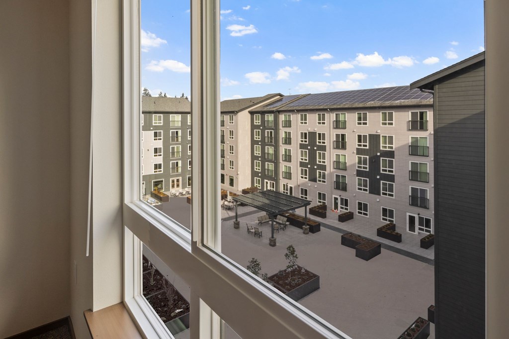 A view from a window of a courtyard with a building in the background.