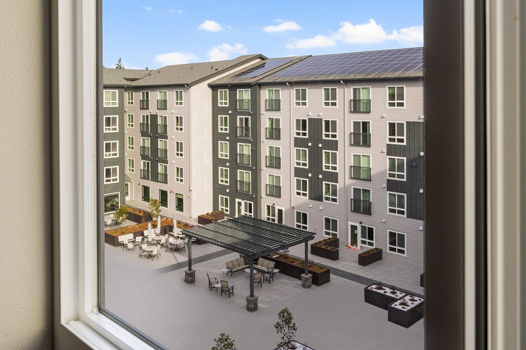 A view from a window of a courtyard with a table and chairs.