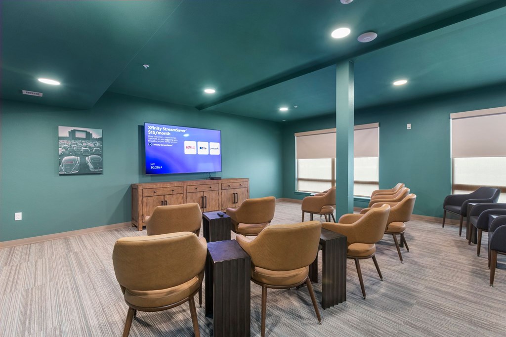 A room with a row of chairs facing a television.