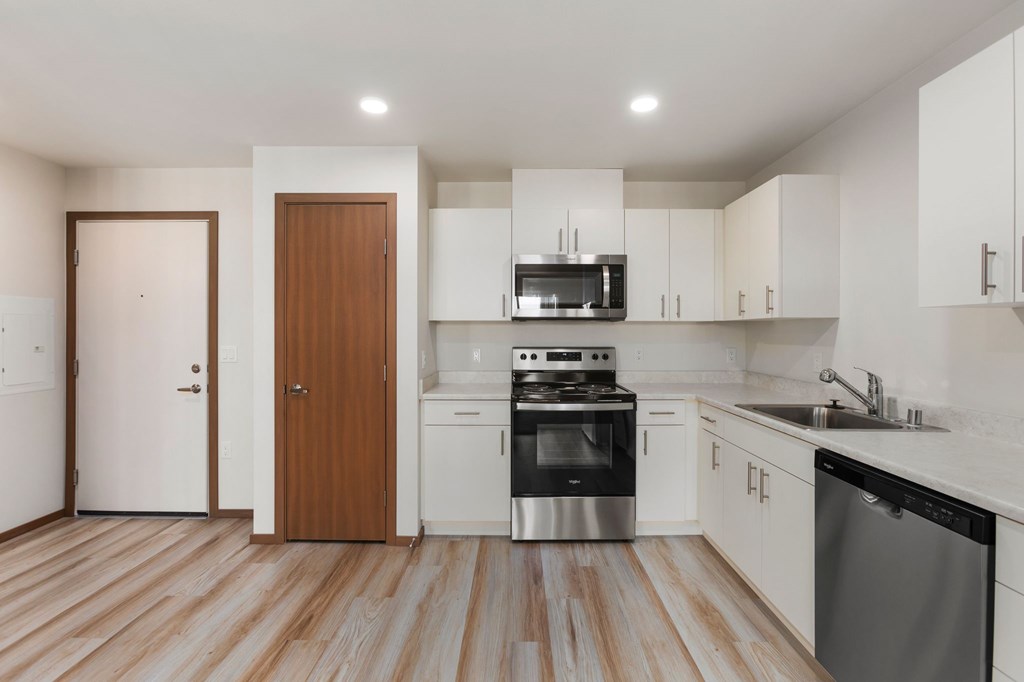 A kitchen with white cabinets and a wooden door.