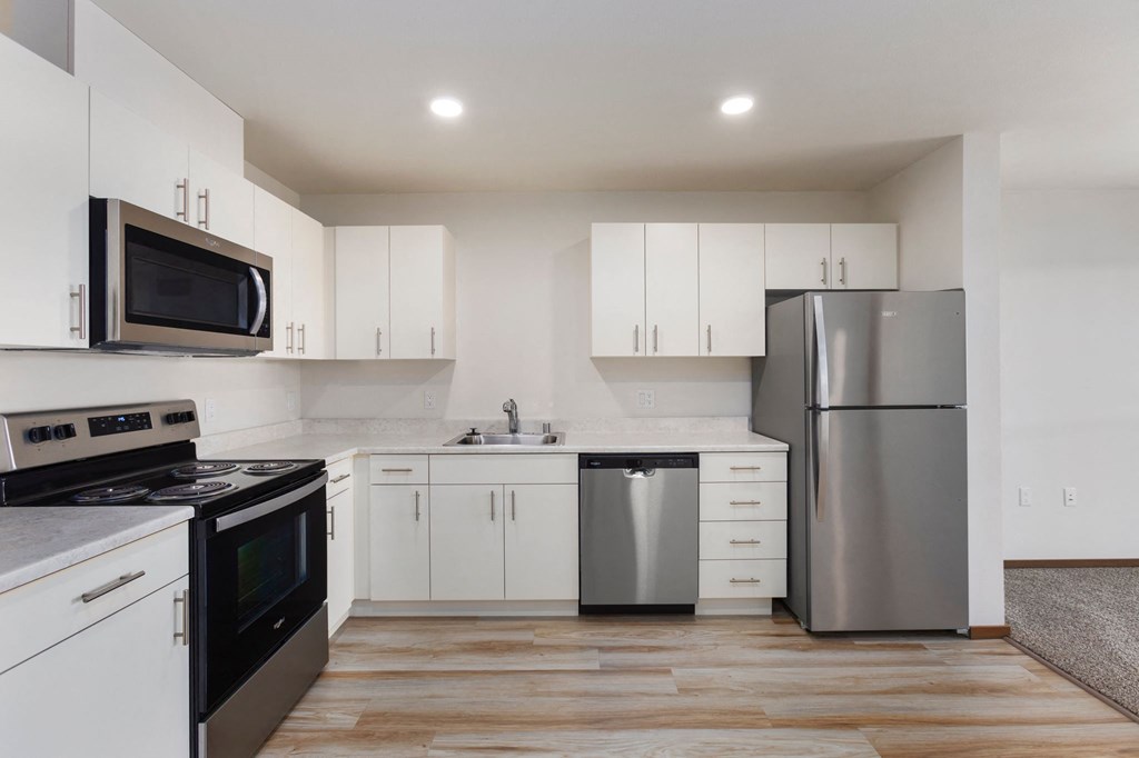 A modern kitchen with white cabinets and stainless steel appliances.