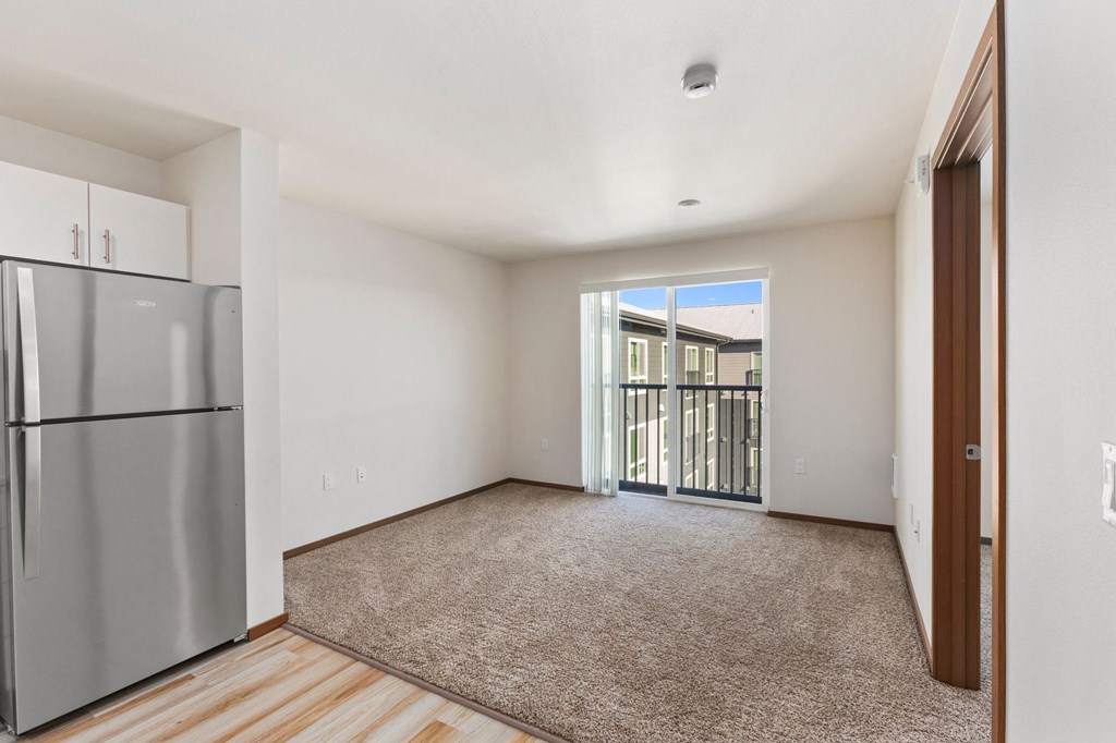 A room with a stainless steel refrigerator and a carpeted floor.