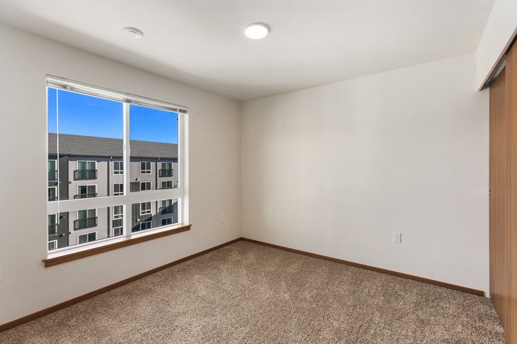 A room with a carpeted floor and a window overlooking a building.
