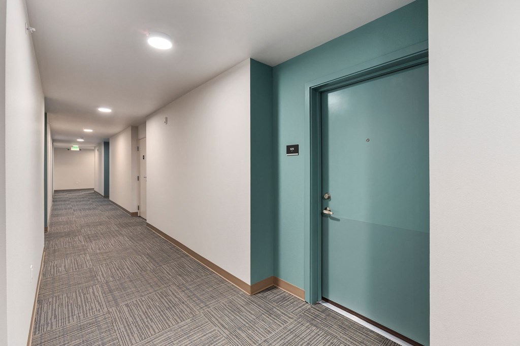 A long hallway with a blue door on the right.