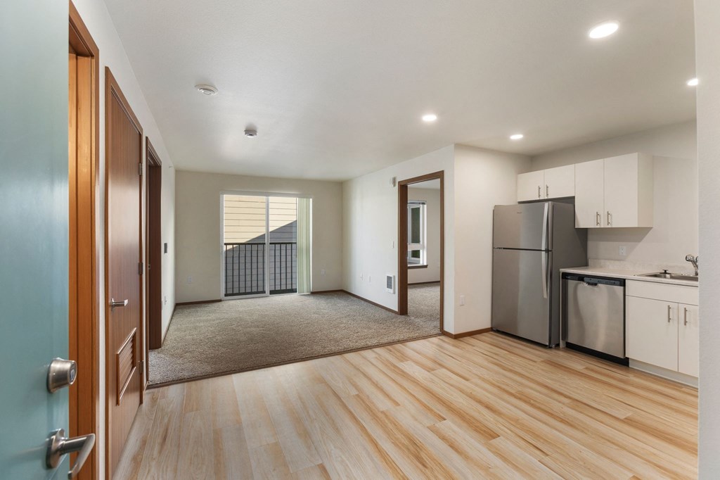 A kitchen with a refrigerator, sink, and cabinets.
