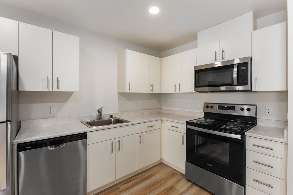 A kitchen with white cabinets and black appliances.
