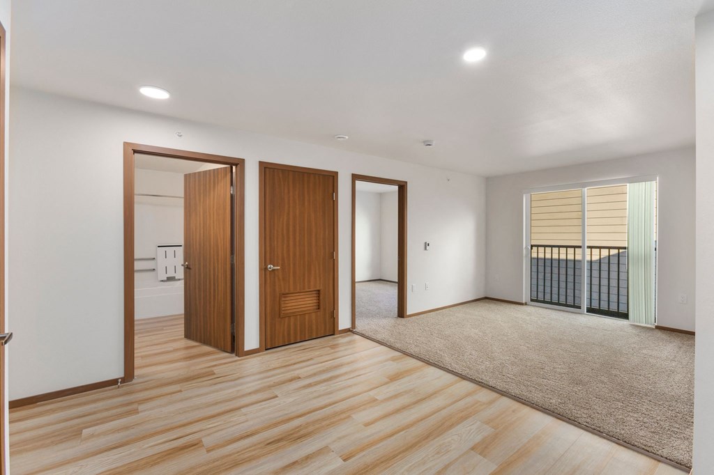 A room with wooden floors and a large window with blinds.
