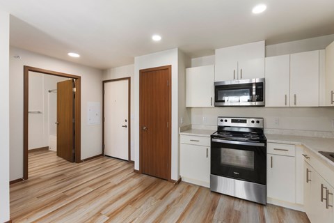 A kitchen with a stove top oven and white cabinets.