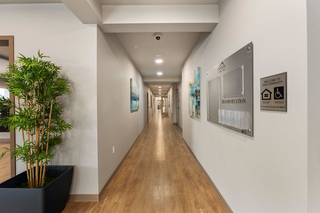 A long hallway with a plant on the left and a sign on the wall that says "Residential".