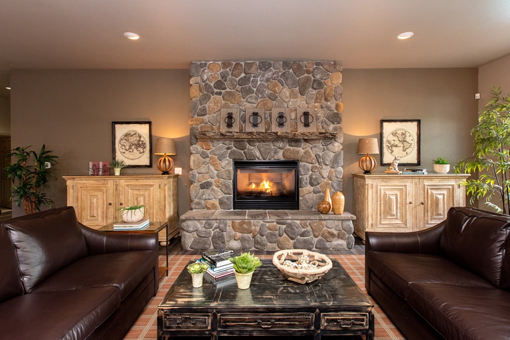 a living room with a stone fireplace and brown couches