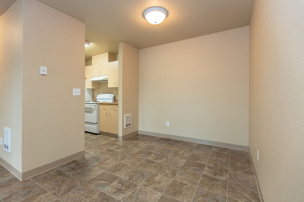 the living room and kitchen of an empty home with tile flooring and white walls