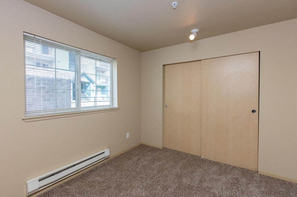 an empty bedroom with a window and a closet