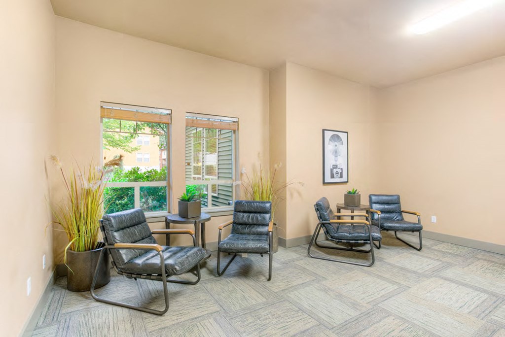 a living room with chairs and a table and windows