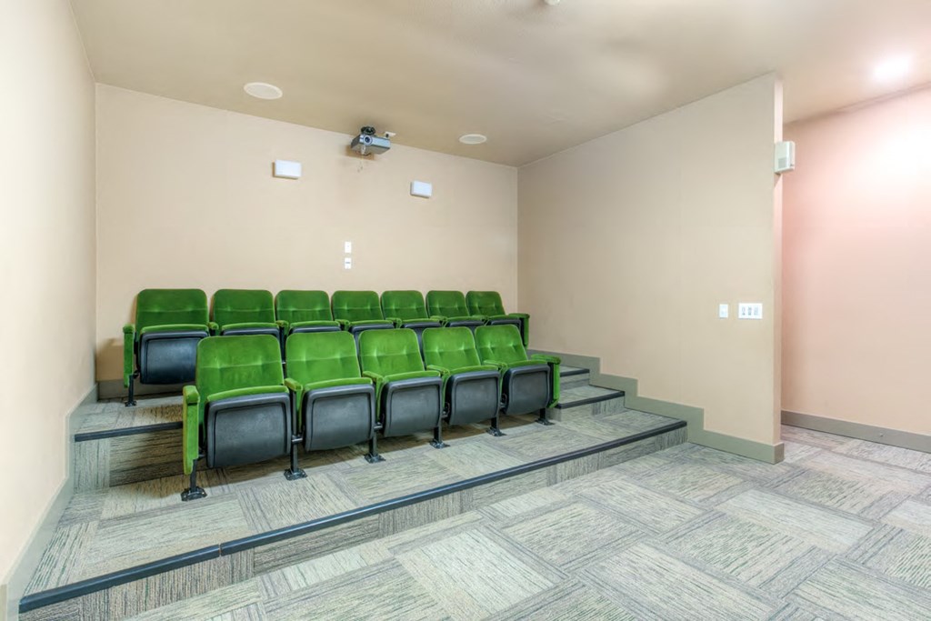 a seating area in a room with green chairs and a staircase