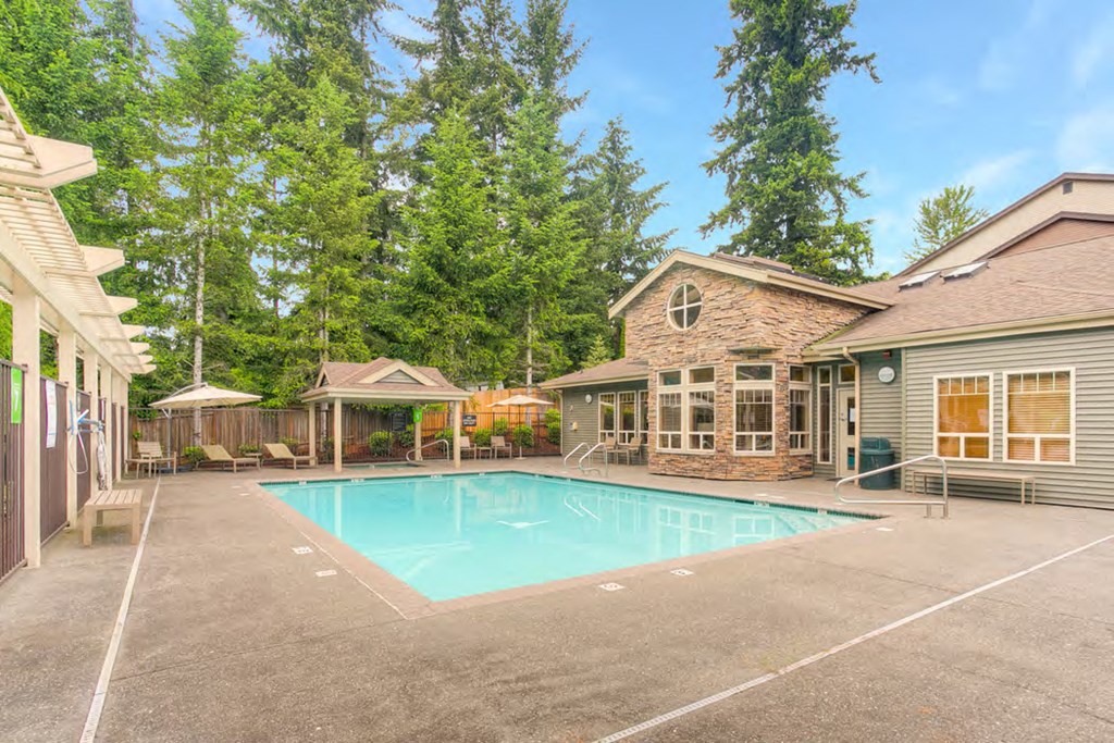 the pool is in the backyard of a house with trees