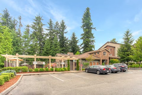 a parking lot with cars in front of a building with trees