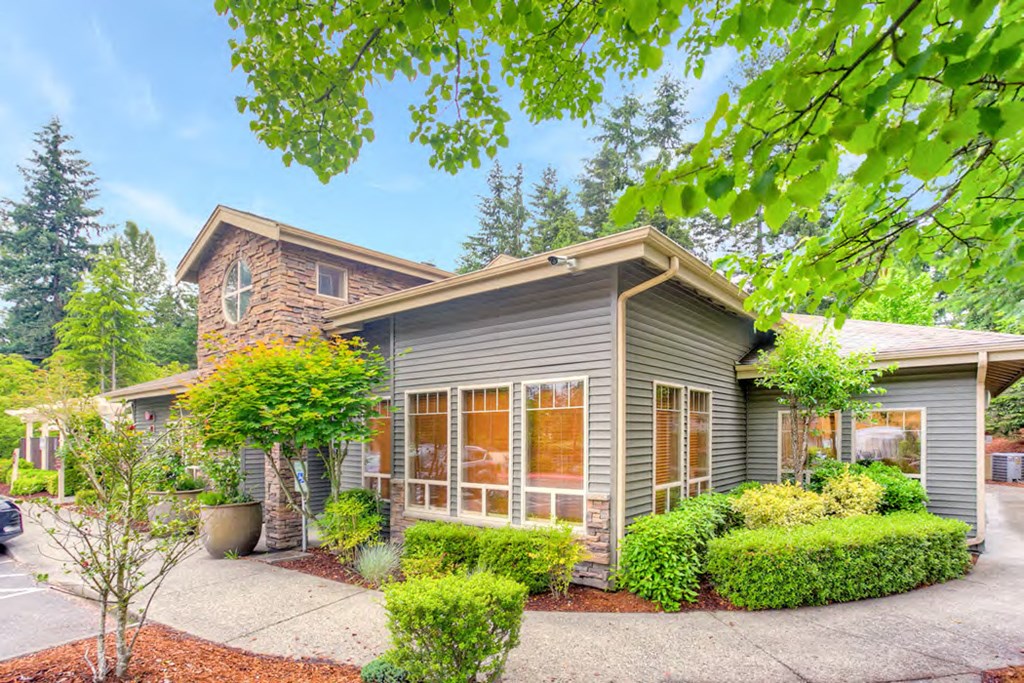 a small gray house with a yard and a driveway