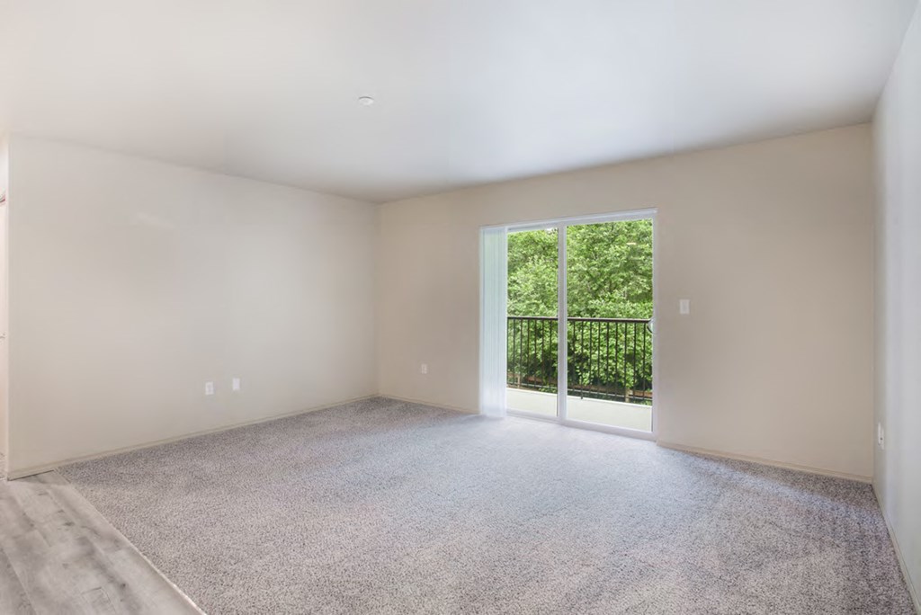 an empty living room with a large window and carpet