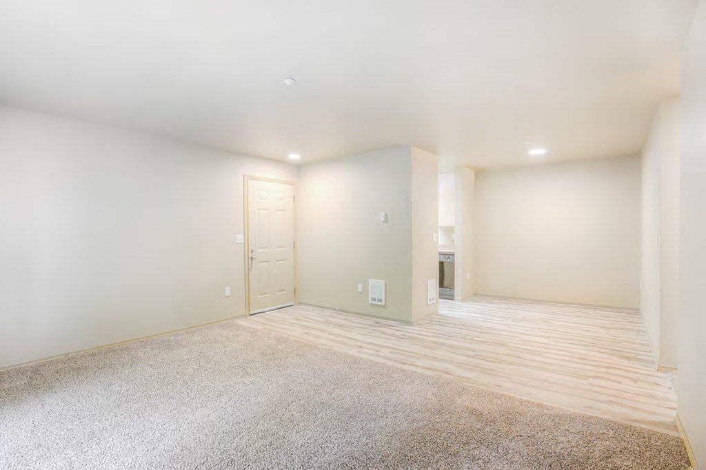 the living room and dining room of a home with white walls and wood flooring