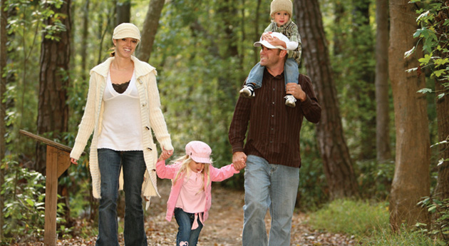 A family of three walking in the woods.
