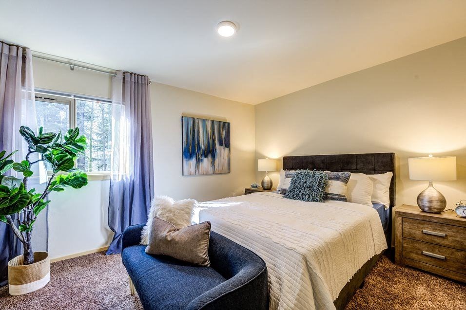 a bedroom with a bed and a chair and a window