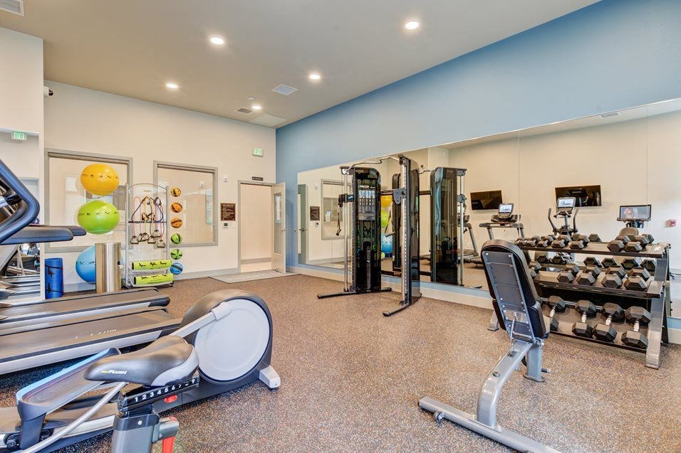 a gym with weights and cardio equipment on the floor and a mirror