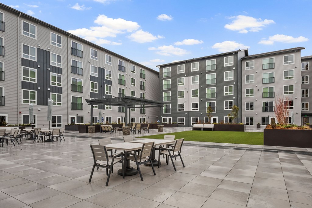 A large courtyard with tables and chairs surrounded by apartment buildings.