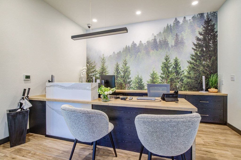 A room with a desk, two chairs, and a large mural of a forest.