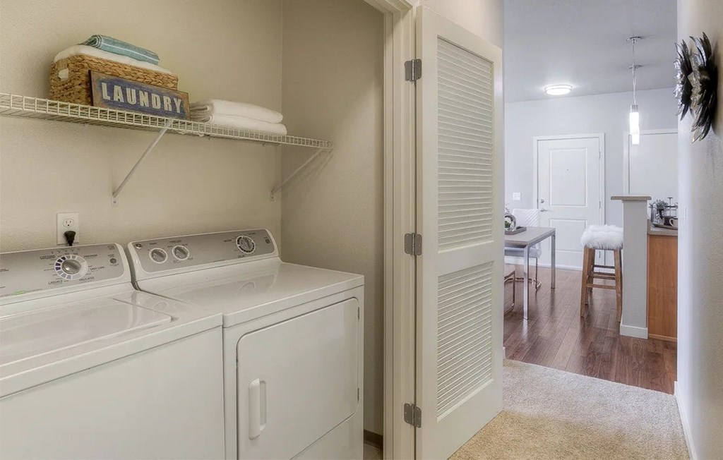 A laundry basket sits on a shelf above a washer and dryer.