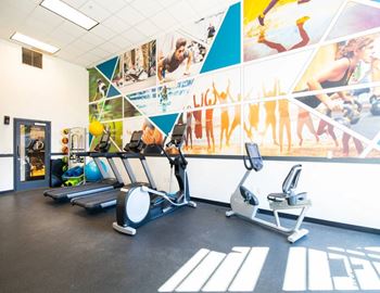 A gym with treadmills, exercise bikes and a wall of motivational posters.
