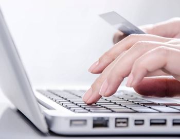 A person's hands are typing on a laptop keyboard.