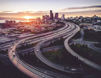 A cityscape with a highway curving through it at sunset.