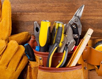 A tool belt with various tools including pliers, scissors, and a tape measure.