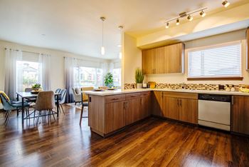 A kitchen with wooden floors and a dining table with chairs.