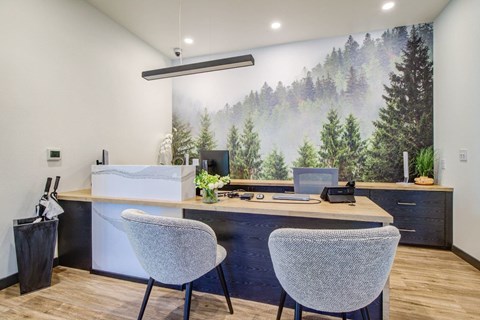 A room with a desk, two chairs, and a large mural of a forest.