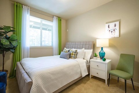 A bedroom with a white bed and a green chair.