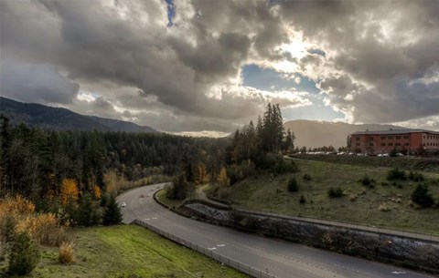 A winding road with a red building on the side and trees on both sides.