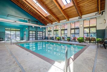 A large indoor swimming pool with a wooden ceiling and a glass wall.