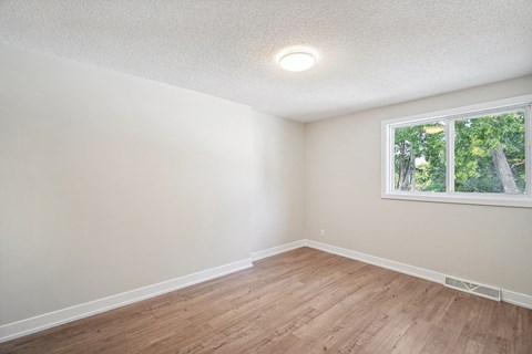 A room with a window and wooden flooring.