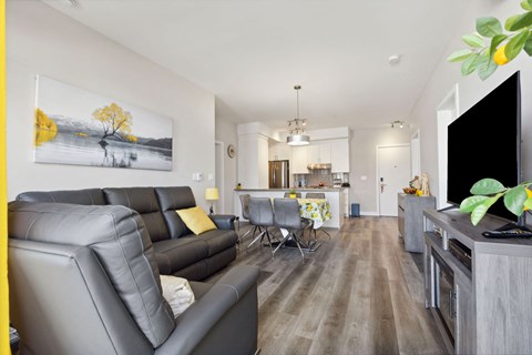A living room with a grey sofa and a painting of a tree on the wall.