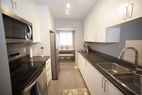 A kitchen with black countertops and stainless steel appliances.