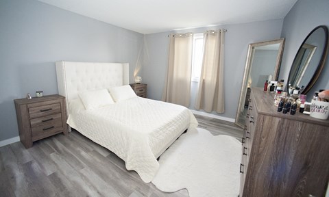 A bedroom with a large bed and a vanity with a mirror.
